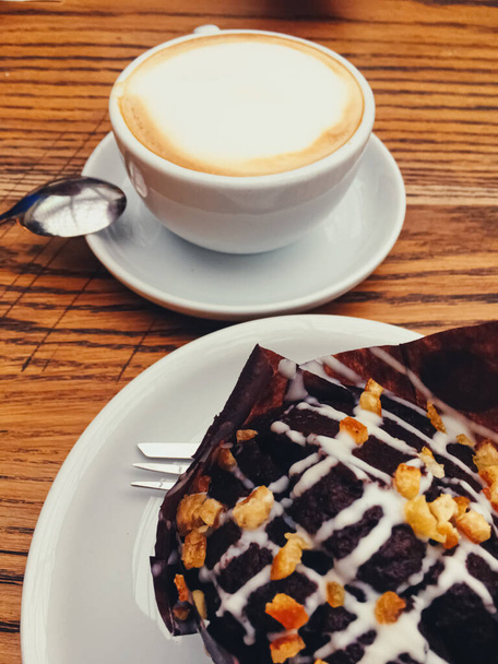 Filiżanka kawy i czekoladowej babeczki na drewnianym stole w kawiarni - Zdjęcie, obraz