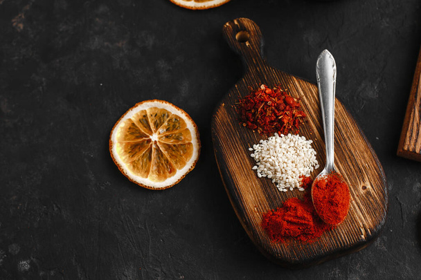 spices for barbecue wings on a wooden Board, on a dark background. Smoked paprika, dried tomatoes, sesame seeds . - Photo, Image