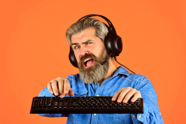 Superior performance. Online gaming. Modern leisure. Run any modern game. Graphics settings pushed to limit. Play computer games. Man bearded hipster gamer headphones and keyboard. Gaming addiction - Foto, afbeelding
