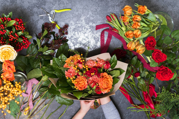 Il concetto di regali e mazzi di fiori per l '8 marzo e la festa della mamma. Fiorista crea un bouquet in un negozio di fiori
. - Foto, immagini