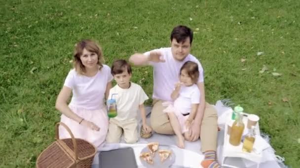 Happy family smiling and waving at picnic - Video