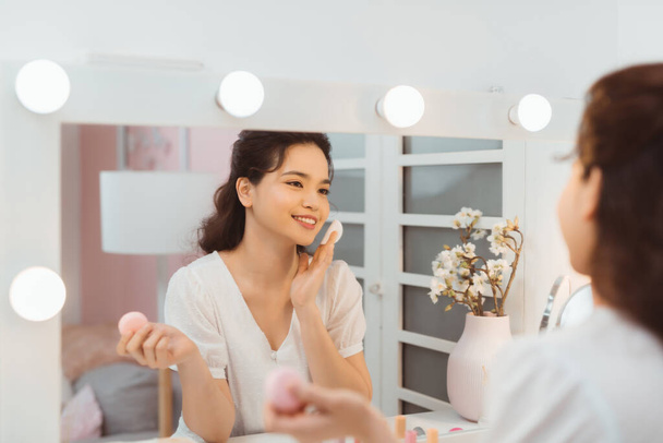 Huidverzorging. Jonge vrouw verwijderen van make-up met behulp van katoenen pad staande in de badkamer. Panorama, lege ruimte - Foto, afbeelding