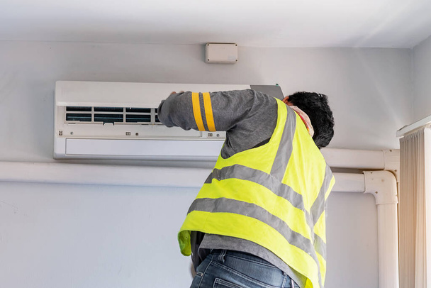 Young Man technicus onderhoud airconditioner binnen. Reiniging, wassen en conditionering Service concept - Foto, afbeelding