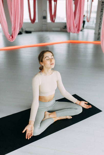 Exercises for self-control in yoga. Bright gym. Relaxed posture during meditation. The girl is sitting on the Mat, relax.  - Fotoğraf, Görsel