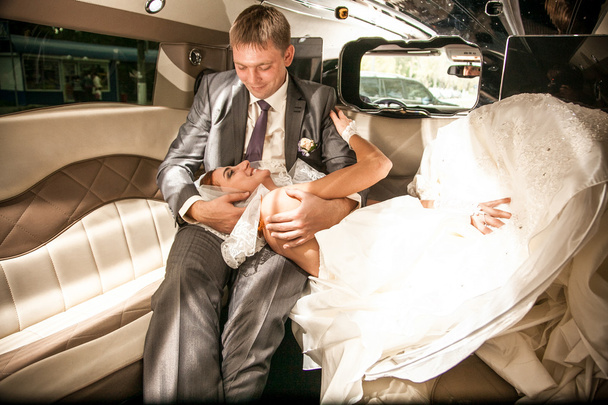 νύφη που βρίσκεται στα πόδια γαμπροί στις λιμουζίνες πίσω κάθισμα - Φωτογραφία, εικόνα