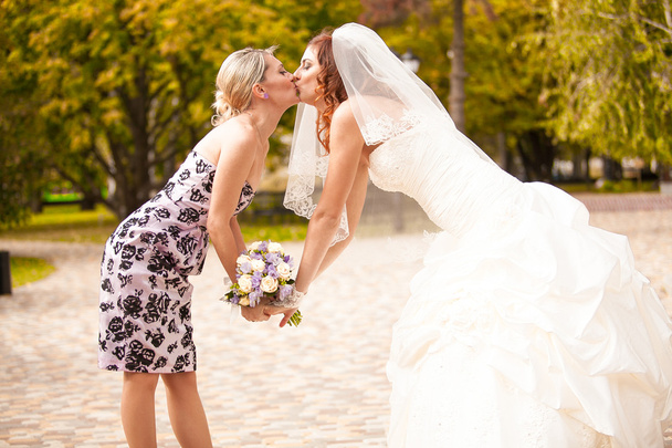 Portrait of bridesmaid kissing beautiful bride - Photo, Image