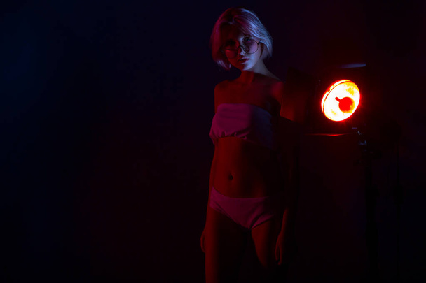 jong mooi vrouw in lingerie poseren in rood terug licht - Foto, afbeelding