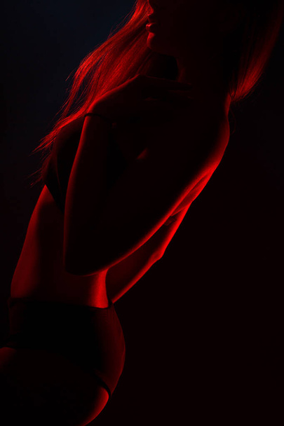 Young beautiful woman in lingerie posing in red back light - Photo, Image