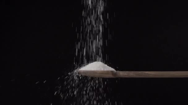 Salt pour from a wooden spoon to bottom in slow motion on a black background  - Кадры, видео
