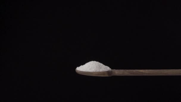 Sůl leje z dřevěné lžíce na dno ve zpomaleném filmu na černém pozadí  - Záběry, video