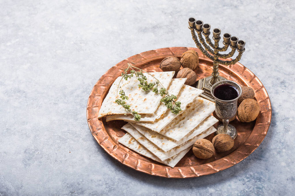 Pascha, het feest van ongezuurd brood, matzah brood en rode wijnglazen op de glanzende ronde metalen schaal. - Foto, afbeelding