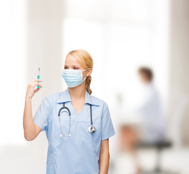 γυναίκα γιατρό ή νοσοκόμα σε μάσκα κρατώντας τη σύριγγα - Φωτογραφία, εικόνα