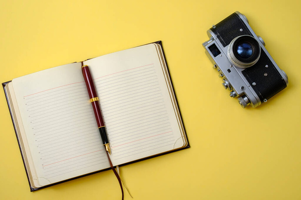 beautiful old vintage retro camera and diary with pen on a yellow background - Foto, immagini