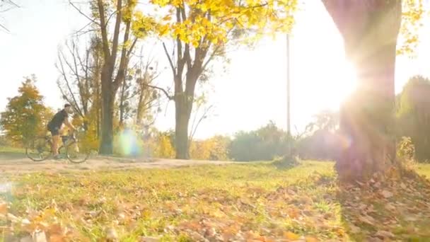 Man rides a bicycle in an outdoor park. Bright sun rays. Slow motion - Video, Çekim