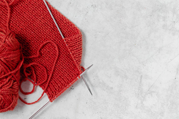 Червоний в'язаний шарф з залізними голкою і вовняними кульками з пряжі. Концепція ручної роботи та вільний час. Копія горизонтального перегляду
 - Фото, зображення