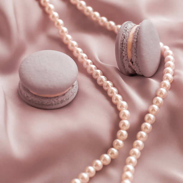 Macaron e gioielli in perle su tessuto di seta, dessert di lusso
 - Foto, immagini