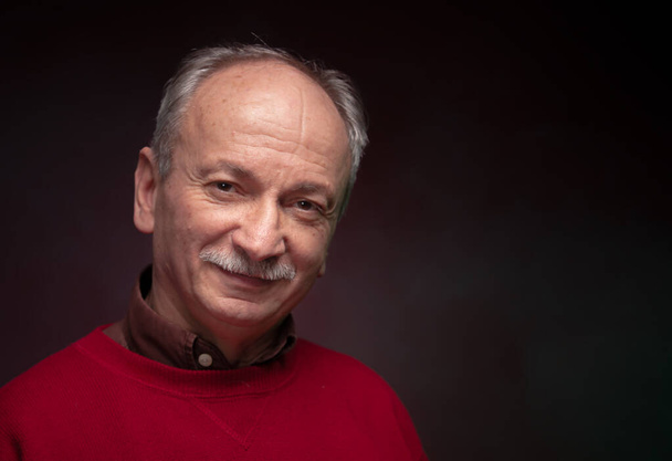 Studio πορτρέτο ενός ηλικιωμένου άνδρα σε ένα κόκκινο πουλόβερ - Φωτογραφία, εικόνα