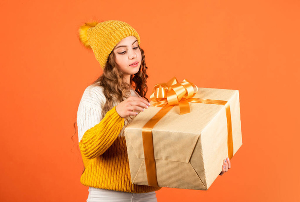 Intrigue concept. Birthday celebration idea. Birthday tradition. Fashionable little girl wear knitted hat and sweater. Birthday surprise. Pretty teen makeup face curly hairstyle. Generous present - 写真・画像