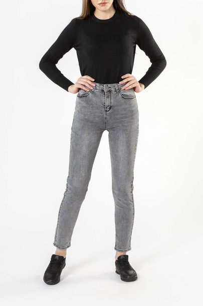 girl in jeans shows jeans on a white background close-up, gray jeans - Φωτογραφία, εικόνα