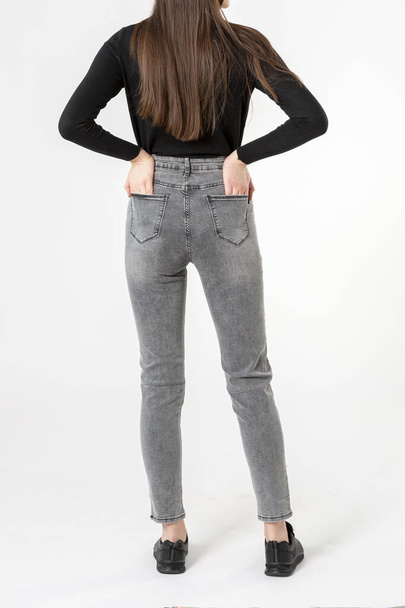 girl in jeans shows jeans on a white background close-up, gray jeans - Foto, afbeelding