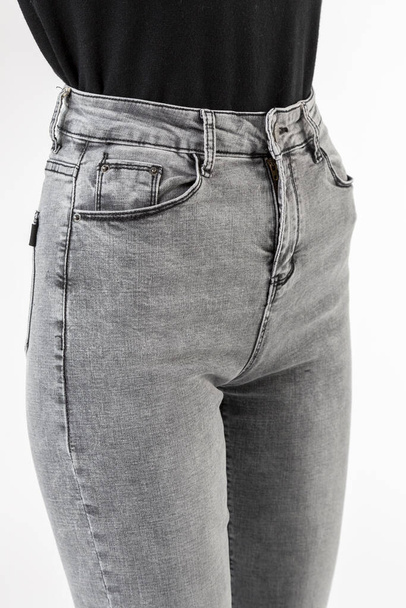 girl in jeans shows jeans on a white background close-up, gray jeans - 写真・画像