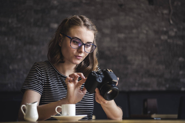 Молода жінка фотографує її фотографії, коли вона сидить, розслабляючи каву
 - Фото, зображення