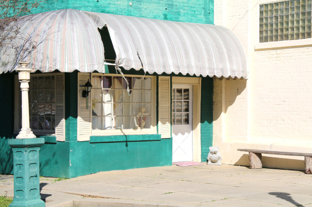 заброшенное здание зеленого магазина с тентами и стеклянным кирпичным окном с тенями
 - Фото, изображение