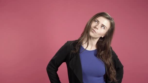Pensive young woman against pink background - Materiał filmowy, wideo