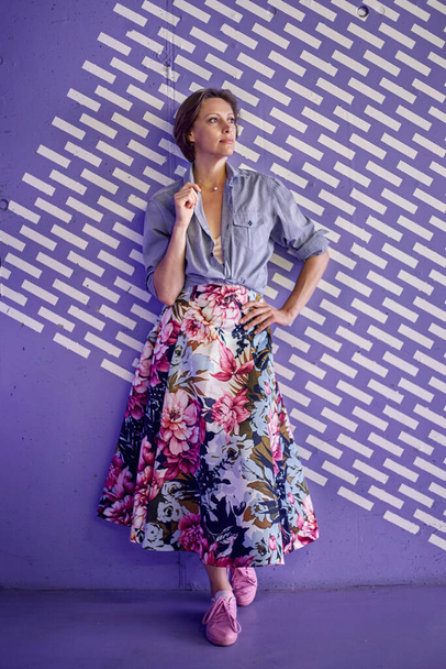 Beautiful young woman in a fashionable shirt and a full-length long color skirt on a purple background. - Foto, Bild