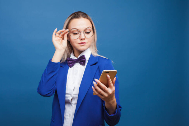 Business lady in stylish blue jacket and bow tie and glasses. Young trending blonde - Фото, зображення