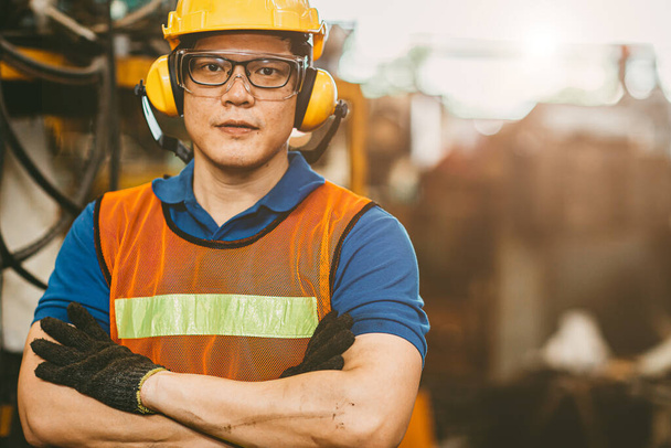 Ingeniero asiático que usa orejeras protección contra el ruido y traje de seguridad que trabaja en retrato de fábrica
. - Foto, imagen