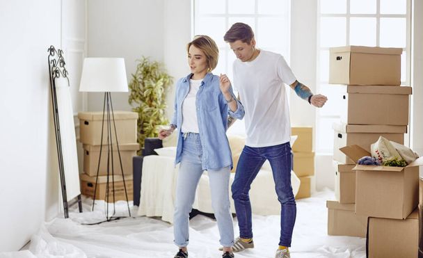 Young happy couple in room with moving boxes at new home - Fotoğraf, Görsel