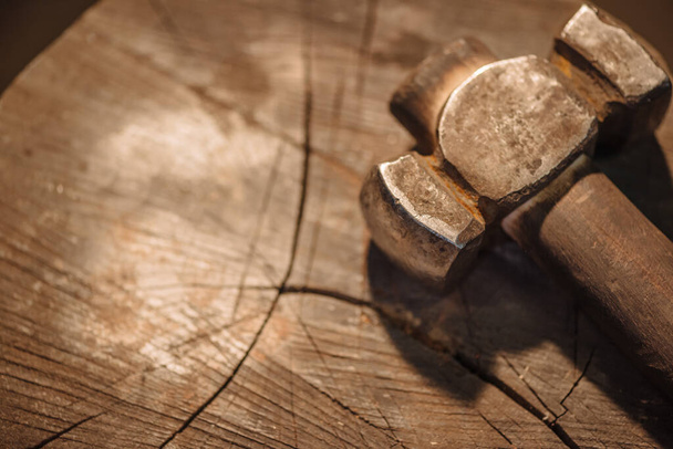 Iron hammer on a wooden stump in the workshop of a blacksmith, close-up. - Foto, afbeelding