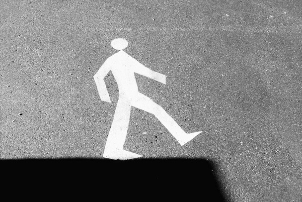 Straßenschild auf dem Asphalt - Spaziergänger am Rand des Schattens. - Foto, Bild