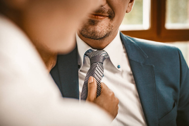 Mujer endereza una corbata de hombre en la oficina
 - Foto, imagen
