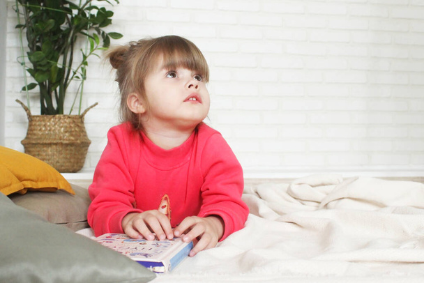the education at home. Sweet girl is studying a book on the floor. Baby girl with a book - Photo, image