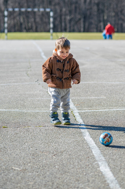 Petit garçon tout-petit, jouant avec la balle sur l'aire de jeux
 - Photo, image