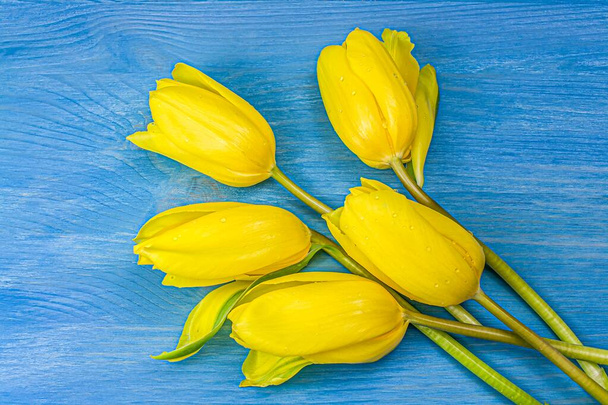 Желтые тюльпаны над деревянным столом, цветы весны
. - Фото, изображение