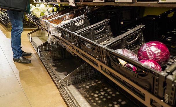 Un comprador en el supermercado europeo eligiendo entre verduras frescas limitadas debido al miedo y pánico de Covid-19
 - Foto, Imagen