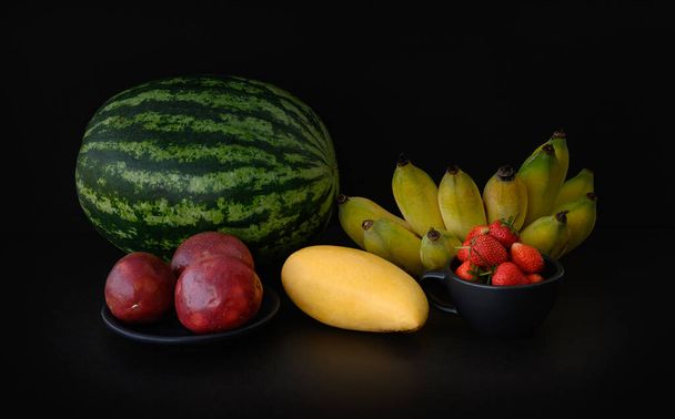 still life tropical fruits - watermelon, mango, passion fruit, strawberry, banana - 写真・画像