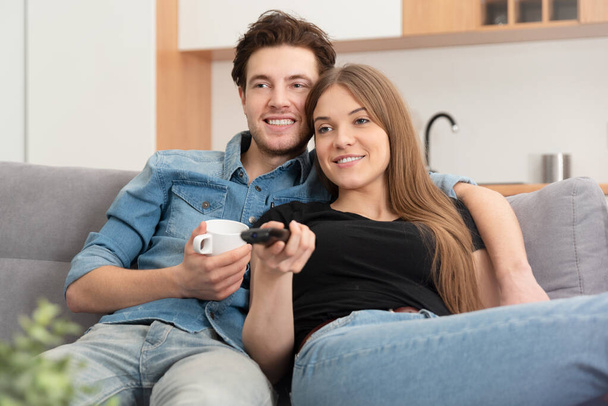 Couple watching TV on sofa. Television, multimedia, leisure concept - Foto, afbeelding