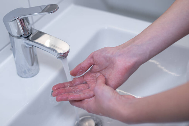 Frau wäscht ihre Hände gründlich mit Seife in der Spüle. Lizenzfreies Archivfoto. - Foto, Bild