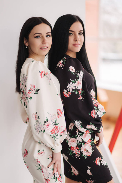 Two fashion brunette models in spring dresses posing in the studio. Black and white background - Fotografie, Obrázek