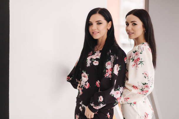 Dois modelos morena moda em vestidos de primavera posando no estúdio. Fundo preto e branco
 - Foto, Imagem