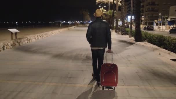 reiziger met een rode koffer kwam tot rust, wandelingen langs de nachtpromenade - Video