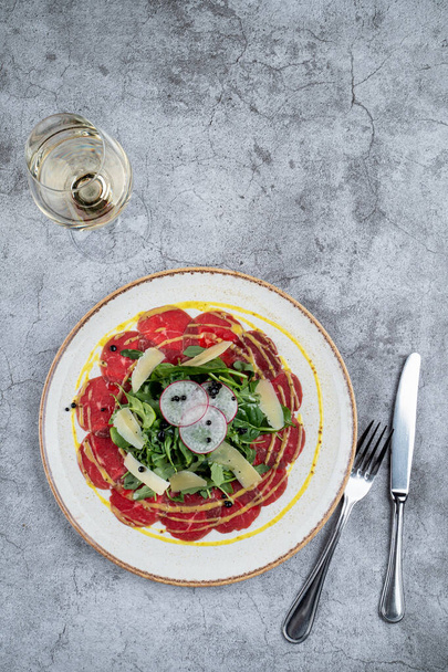 Gourmet-Snack: Rindfleisch-Carpaccio mit einem Bund Spinat und Parmesanscheiben - Foto, Bild