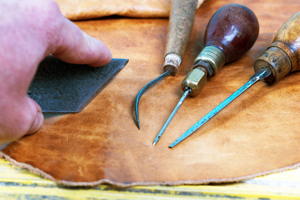 Narzędzia rzemieślnicze skóry na tle drewnianych. Skóra craftmans biurko. Kawałek Ukryj i pracy ręcznie wykonane narzędzia na stół roboczy - Zdjęcie, obraz