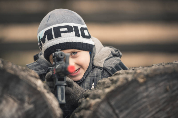 niño de cinco años jugando con un juguete de rifle
 - Foto, Imagen