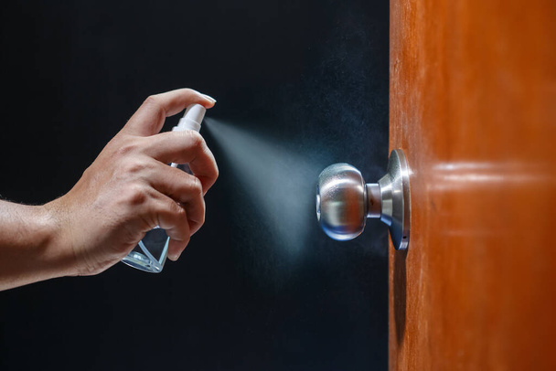 Pomo de la puerta de limpieza con spray de alcohol para la prevención de Covid-19 (Coronavirus). - Foto, imagen