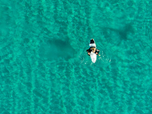 Aerial view of surfers waiting, paddling and enjoying waves in a beautiful blue water  - Фото, зображення